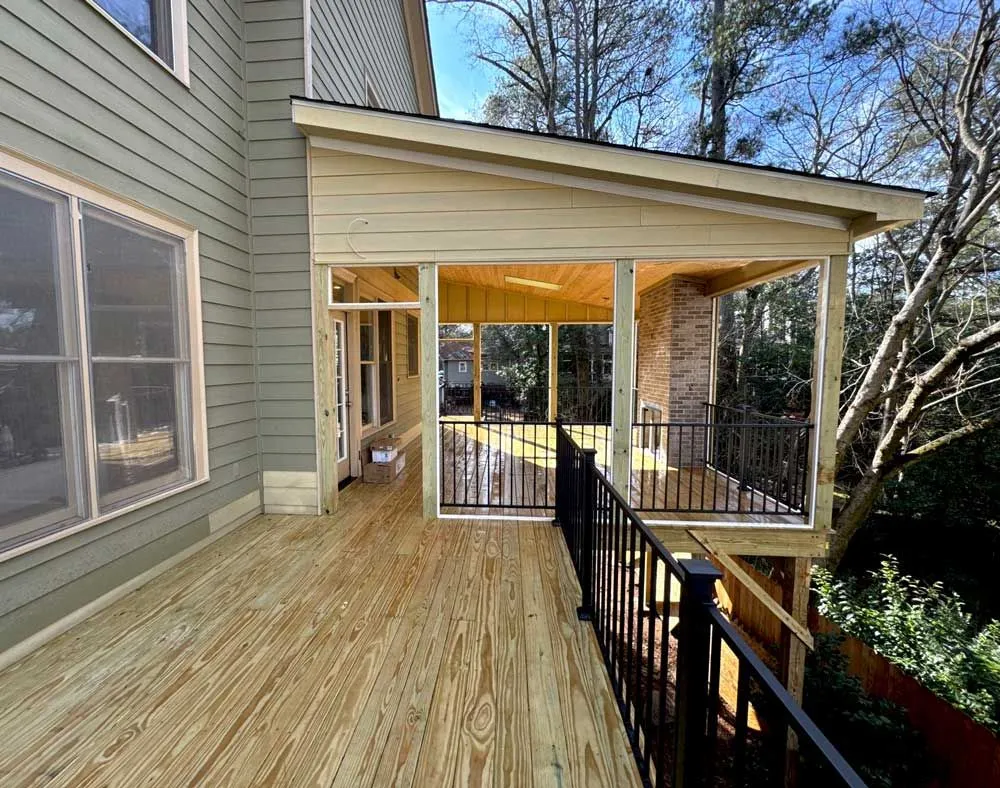 Large elevated wooden deck leading into a screened-in porch with a brick fireplace.