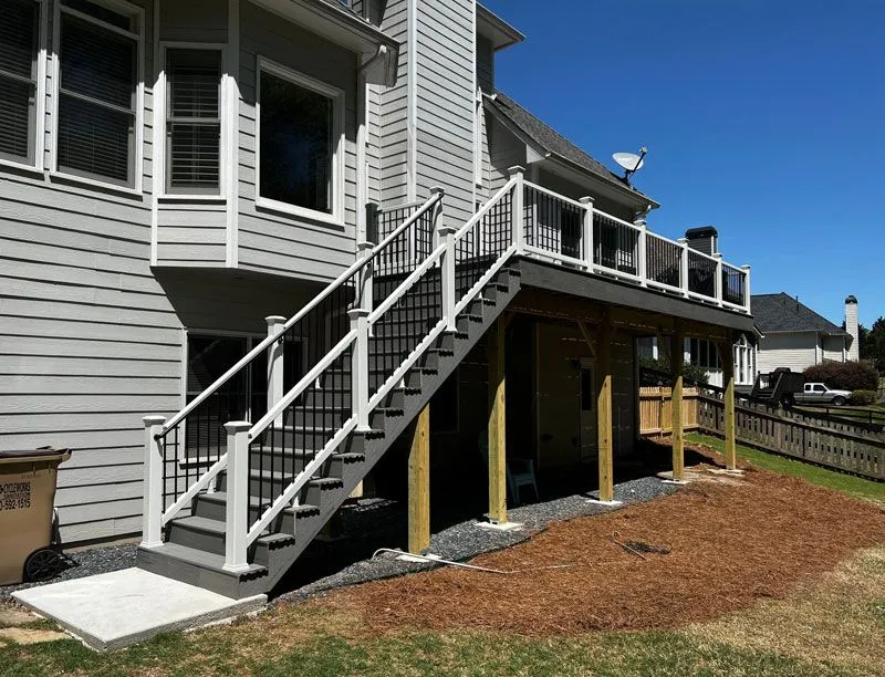 Newly constructed gray composite deck with white railings on a suburban home.