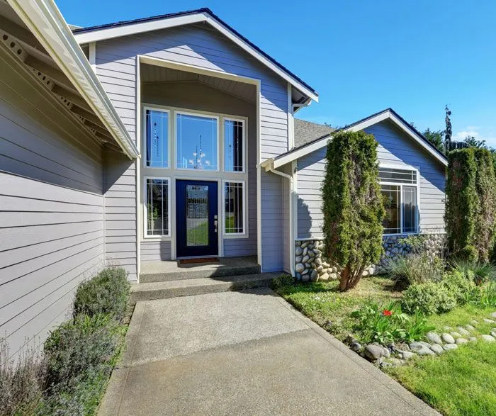 Gray siding home with a tall vaulted entryway and dark blue front door.