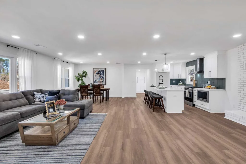 Bright open-concept interior featuring a modern white kitchen and a gray sectional sofa.