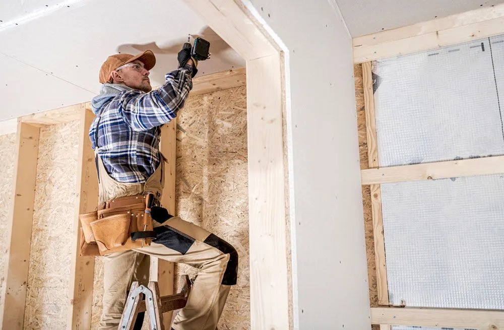Professional contractor installing mineral wool insulation in a home attic.