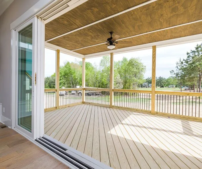Modern screened porch with light wood decking and a dark ceiling fan.