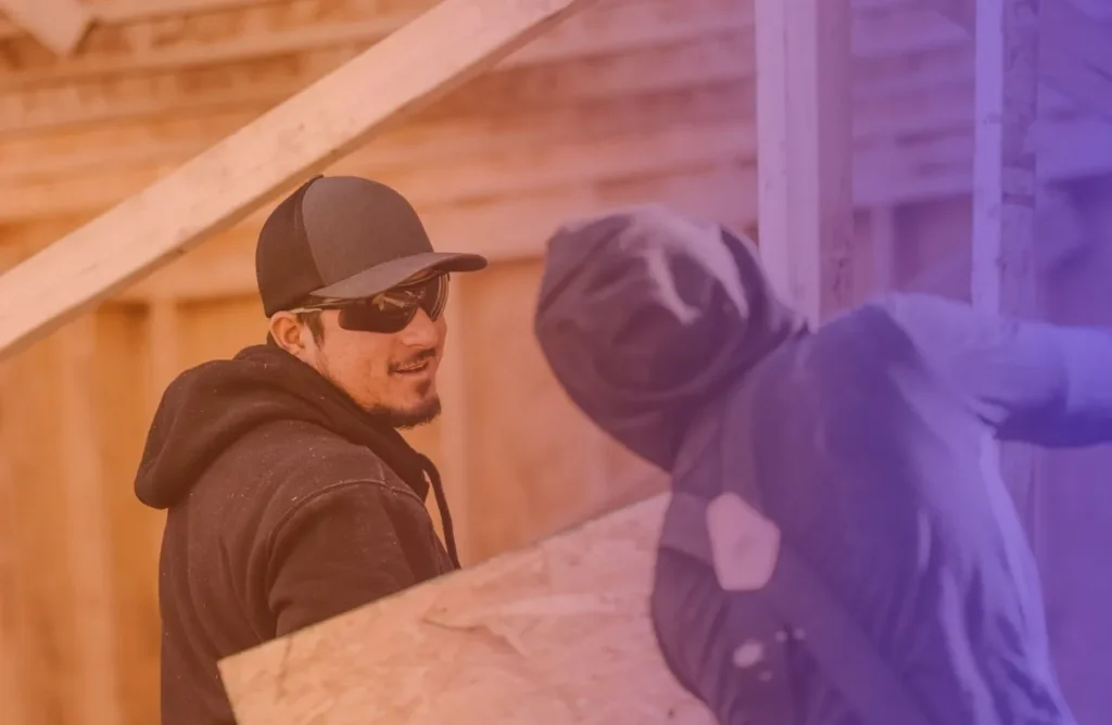 Two construction professionals installing a new window on a home exterior.