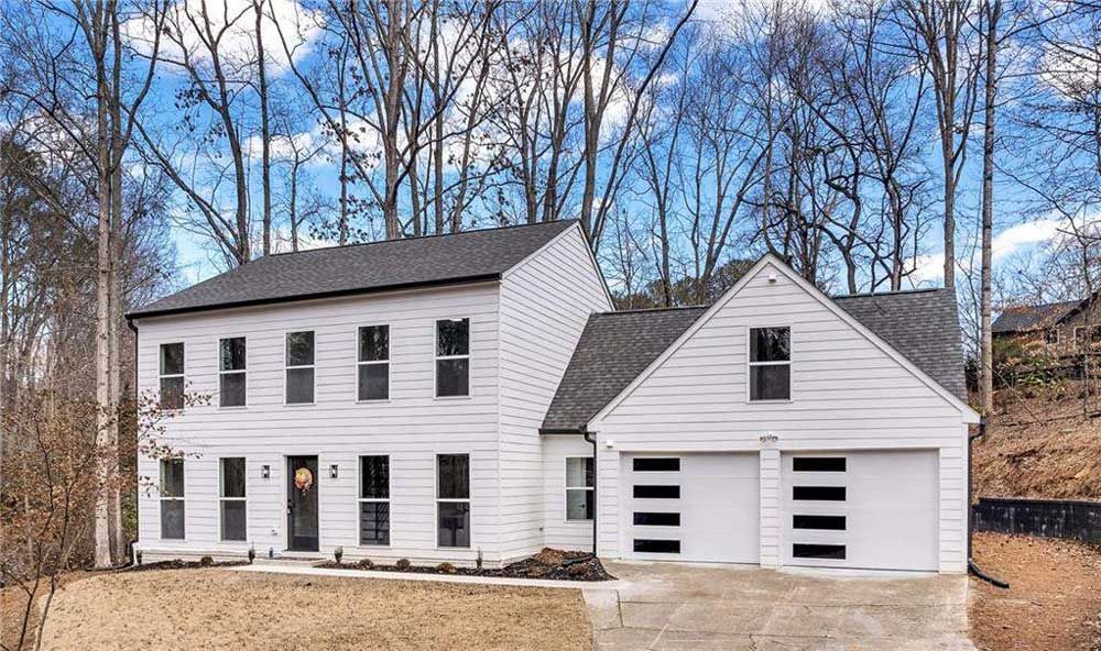 Exterior of a white two-story house with black windows and a three-car garage.