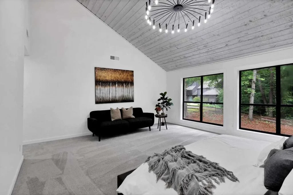 Spacious bedroom featuring a vaulted gray wood plank ceiling and large windows.