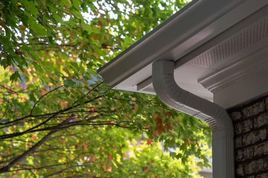 Close-up of a high-quality white gutter and downspout system installed on a house.