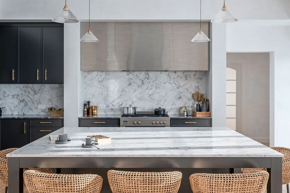 Luxury kitchen featuring a large marble island, black cabinets, and woven bar stools.