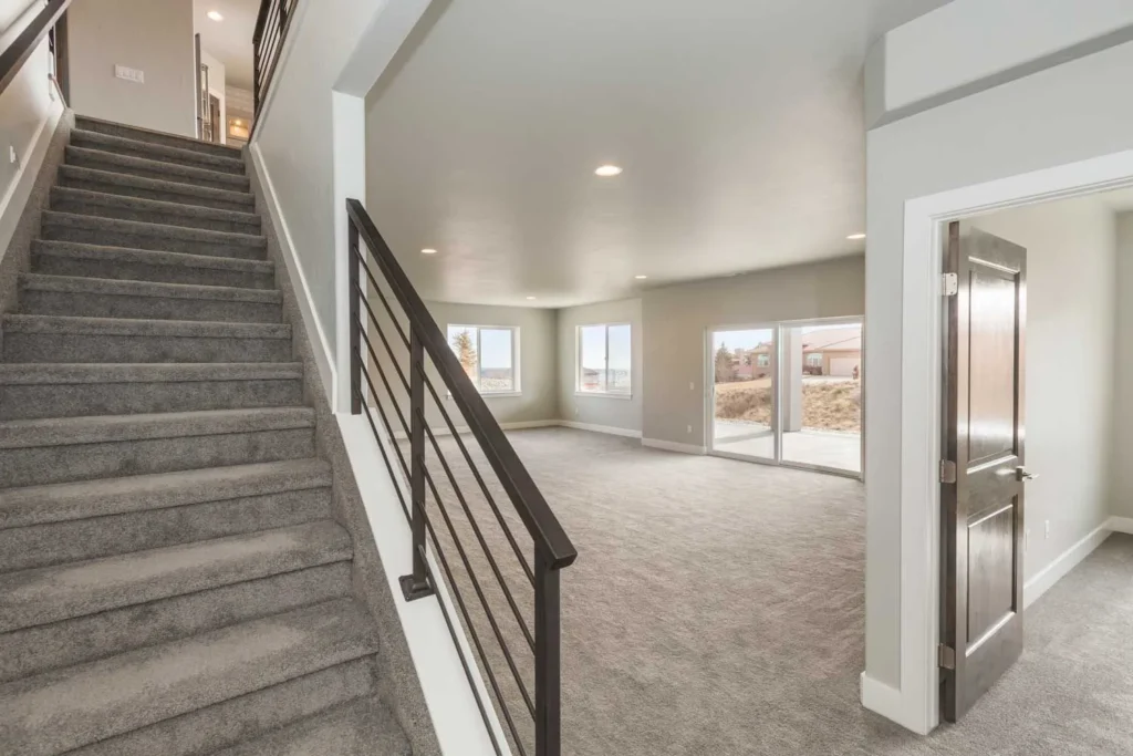 Carpeted staircase with black metal railing leading into an open living space.