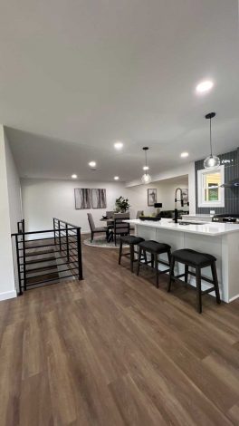 Living area with wood flooring and a black horizontal metal railing staircase.